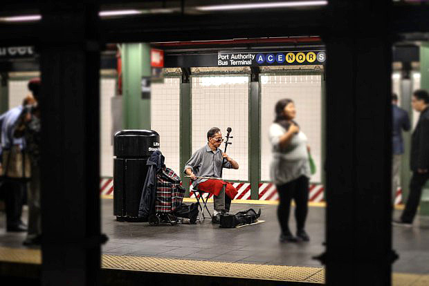 A soloist brings culture to the 42nd Street train platform with his Erhu, a Chinese string instrument.